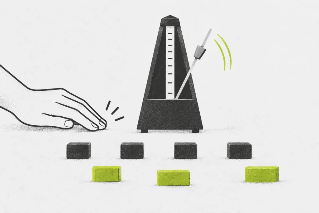 A hand tapping beside a mechanical metronome and two rows of evenly spaced practice blocks.