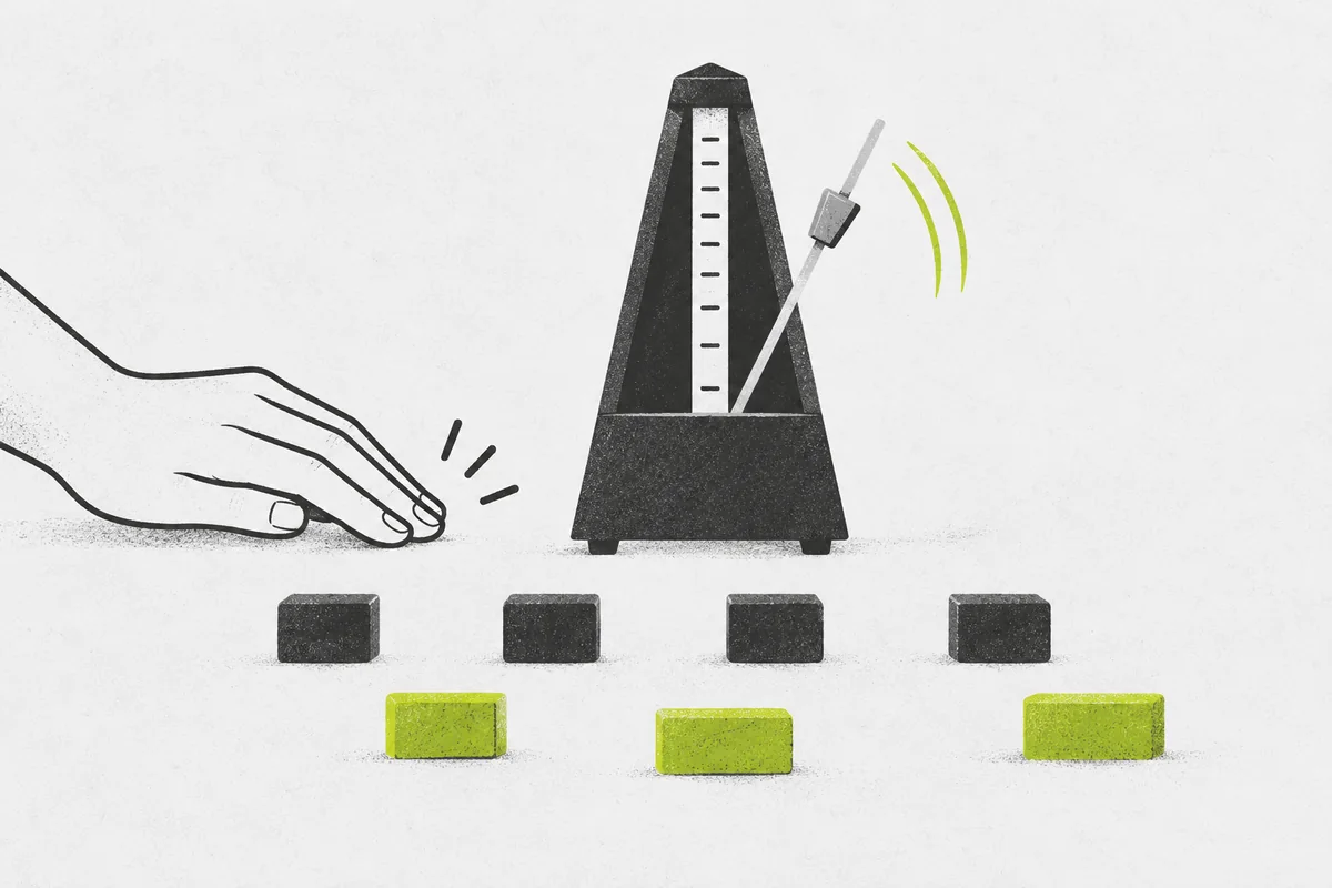 A hand tapping beside a mechanical metronome and two rows of evenly spaced practice blocks.